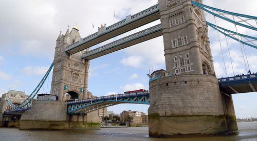Low angle view of tower bridge over thames river against cloudy sky