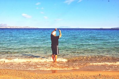 Rear view of person standing on beach against sky