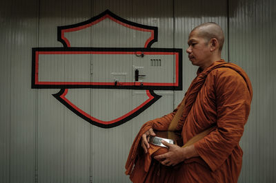 Side view of monk standing against wall