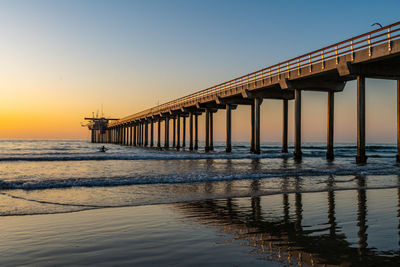 Pier over sea against clear sky during sunset