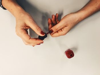 Cropped hands of woman applying nail polish at table