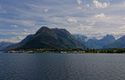 Scenic view of sea by mountains against sky