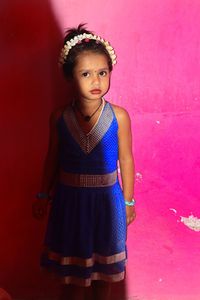 Portrait of teenage girl standing against red wall