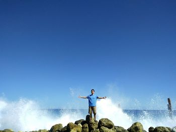 Man standing in sea against clear blue sky