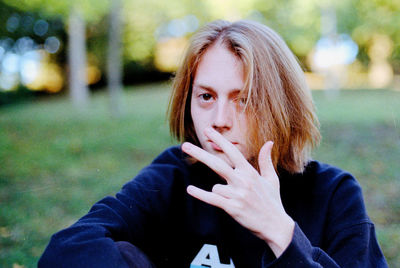 Portrait of woman gesturing while sitting in park