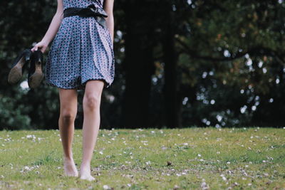 Low section of girl walking on field with barefoot