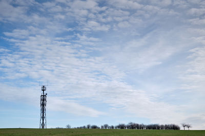 Low angle view of electricity pylon on field against sky