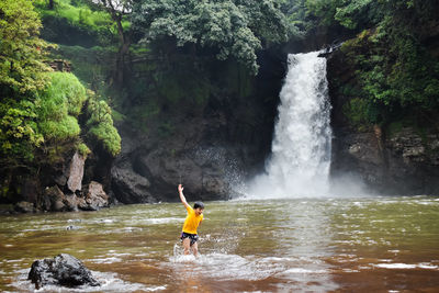 Boy surfing on rock in waterfall