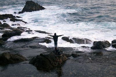 Rear view of a silhouette man overlooking calm sea