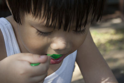 Close-up of boy eating food with spoon while sitting outdoors