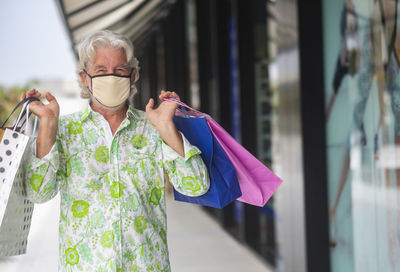 Portrait of smiling man holding shopping bag outdoors