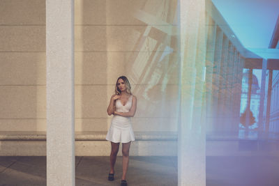 Portrait of young woman standing against wall