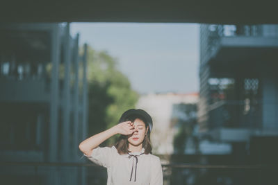 Close-up of young woman standing against buildings in city