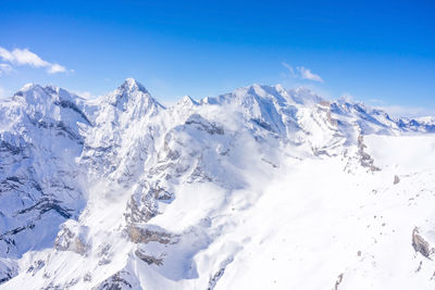 Scenic view of snowcapped mountains against blue sky