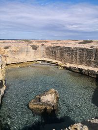 Rock formations by sea against sky