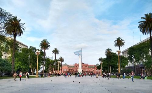 People by palm trees against sky