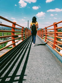 Rear view of woman standing on footbridge