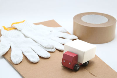 Gloves with toy truck and cardboard over white background
