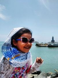 Girl with sunglasses on beach against sky