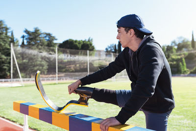 Athlete with prosthetic leg while standing by railing on field