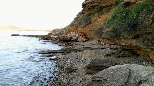 Rock formations by sea against clear sky