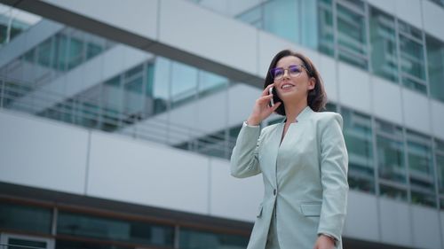 Caucasian female business leadership person who talking on cell phone dressed suit