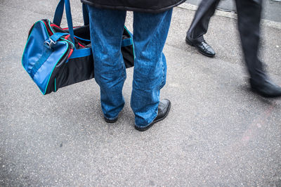 Low section of man with luggage standing on road