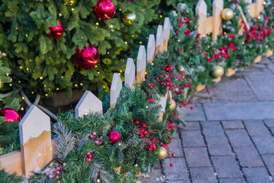 Christmas outdoors decoration of fence. branches with balls and garland