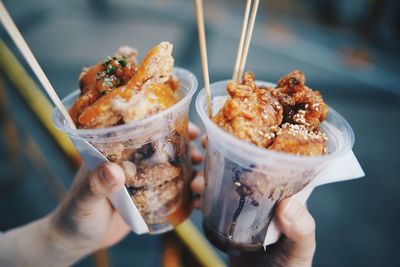 Close-up of hand holding food in disposable glasses outdoors