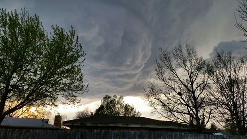Low angle view of bare tree against cloudy sky