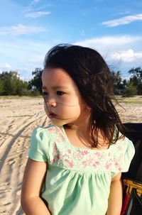 Cute girl looking away while standing at beach