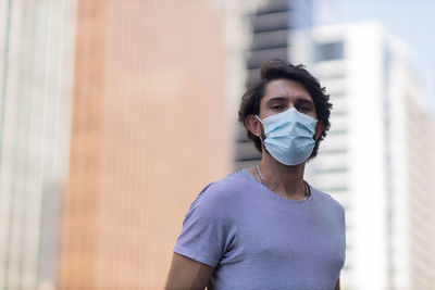 Portrait of a handsome man wearing a medical protective mask on his face on a big city street