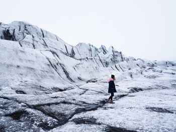 Rear view of man standing on mountain against clear sky