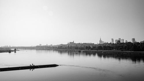 Scenic view of river by buildings against clear sky