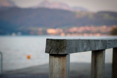 Close-up of wooden post at lake against sky