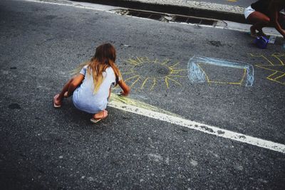 High angle view of girls chalk drawing on road