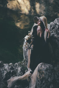 Woman standing on rock against trees