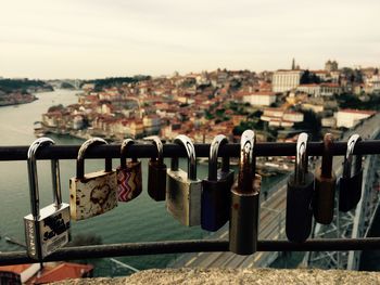 Close-up of love locks on bridge over river against sky