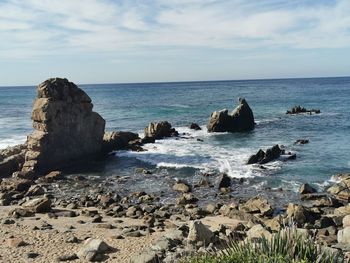 Scenic view of rocks on beach against sky