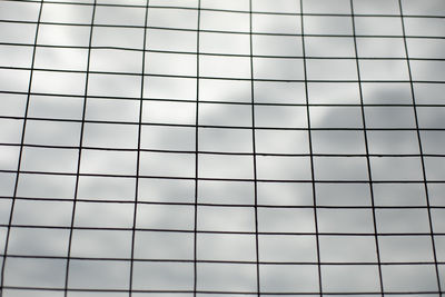 Grid against gray sky. texture of cell is made of steel. repeating elements of straightness. 