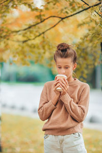 Girl drinking coffee while standing at park