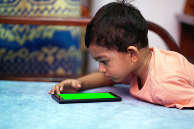 Boy looking at smart phone while lying on floor