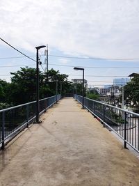 Empty footpath amidst bridge against sky
