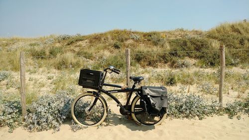 Black bicycle parked arid field during sunny day