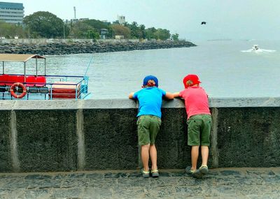 Rear view of men on boat against sea