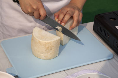 Midsection of chef cutting dikon radish on board