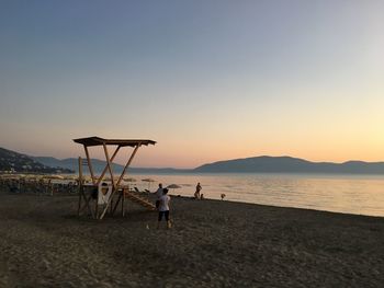 People on beach against sky during sunset