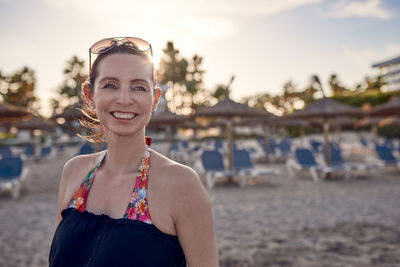 Cheerful woman looking away while standing at beach during sunset
