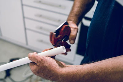 Midsection of man holding pipe