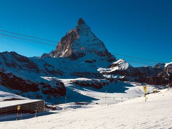 Scenic view of snowcapped mountains against clear blue sky